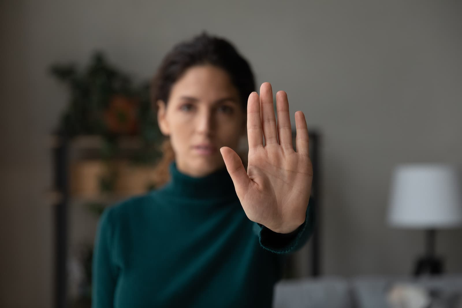 A young woman holding up her hand — a quiet gesture of strength and a call to stop.